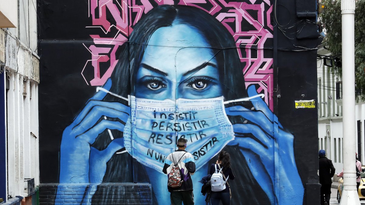 Un mural en Bogotá, donde una mujer sostiene una mascarilla, hace referencia a la terrible pandemia de la COVID-19 en el mundo.