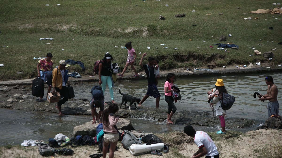 Un grupo de venezolanos atraviesan un riachuelo en la frontera entre Ecuador y Perú.