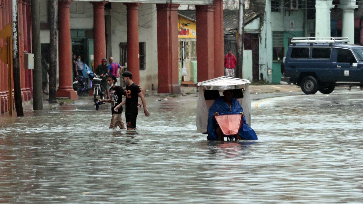 Varias personas caminan por una calle llena de agua, hoy en La Habana (Cuba).