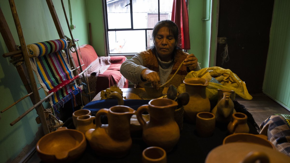 Julia Matamala Llancao, una alfarera, mientras trabaja en la confección de piezas con greda y ücu, un tipo de arena fina que le otorga brillo, en la comunidad Quechocahuín,. EFE/