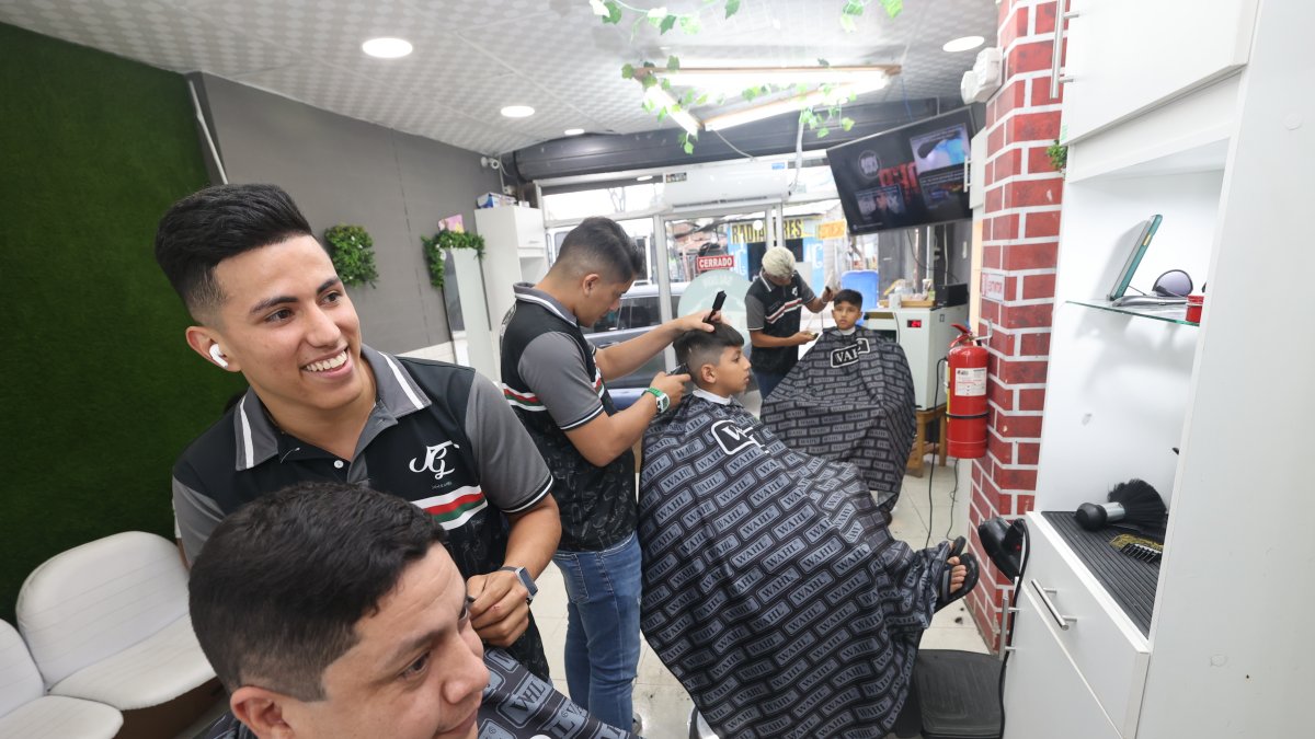 1. En 2022. Actualmente, Jaiser Gómez (de pie) tiene su propia barbería donde le da trabajo a tres jóvenes. Dos de ellos ecuatorianos y un coterráneo. Algunos de los muebles fueron donados por sus clientes.