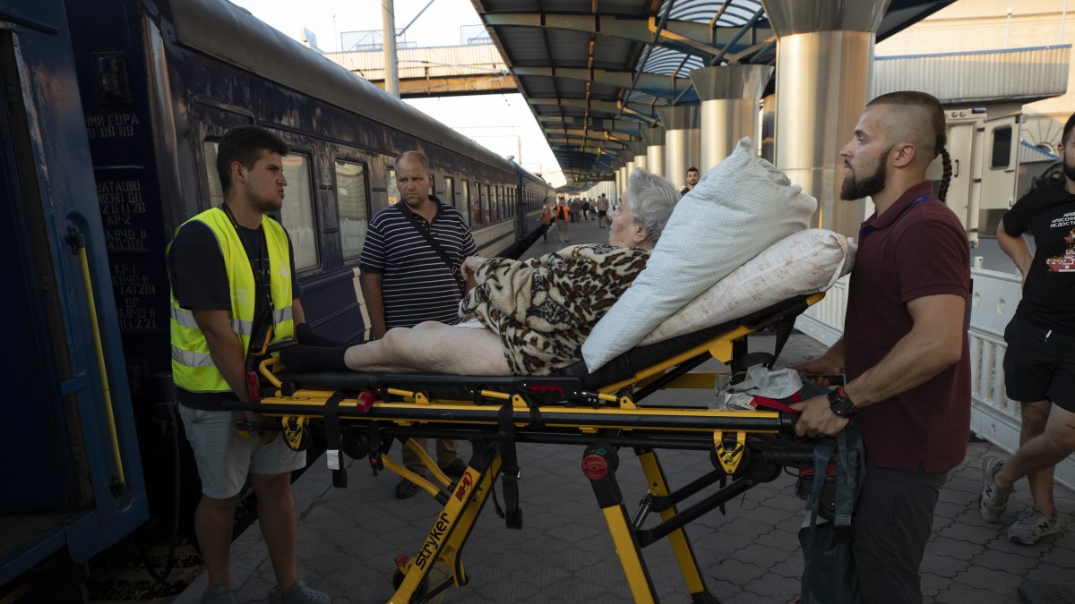 Voluntarios suben a una anciana a un vagón, donde van las personas que huyen de las zonas de combates en un tren, en Dnipro (Ucrania). EFE/