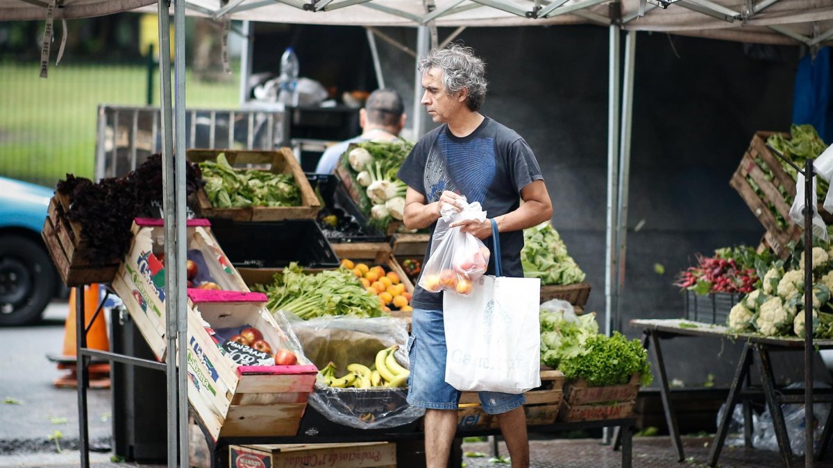 personas mientras realizan las compras en una feria callejera de venta de frutas y verduras en Buenos Aires (Argentina).