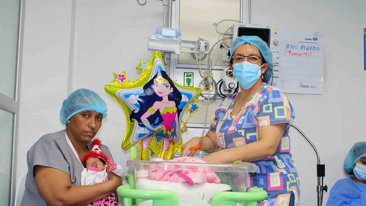 Fotografía cedida por el Hospital General Teófilo Dávila que muestra a Yanelys (i) mientras sostiene a su hija Milagros junto a la pediatra Catalina Campoverde, el 7 de julio de 2022, dentro de ese centro médico en Machala, provincia de El Oro (Ecuador).