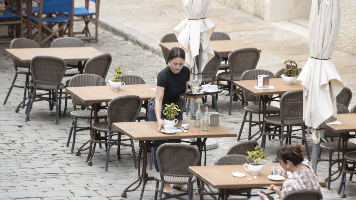 Imagen de archivo de una trabajadora recoge una mesa de una terraza en un bar.