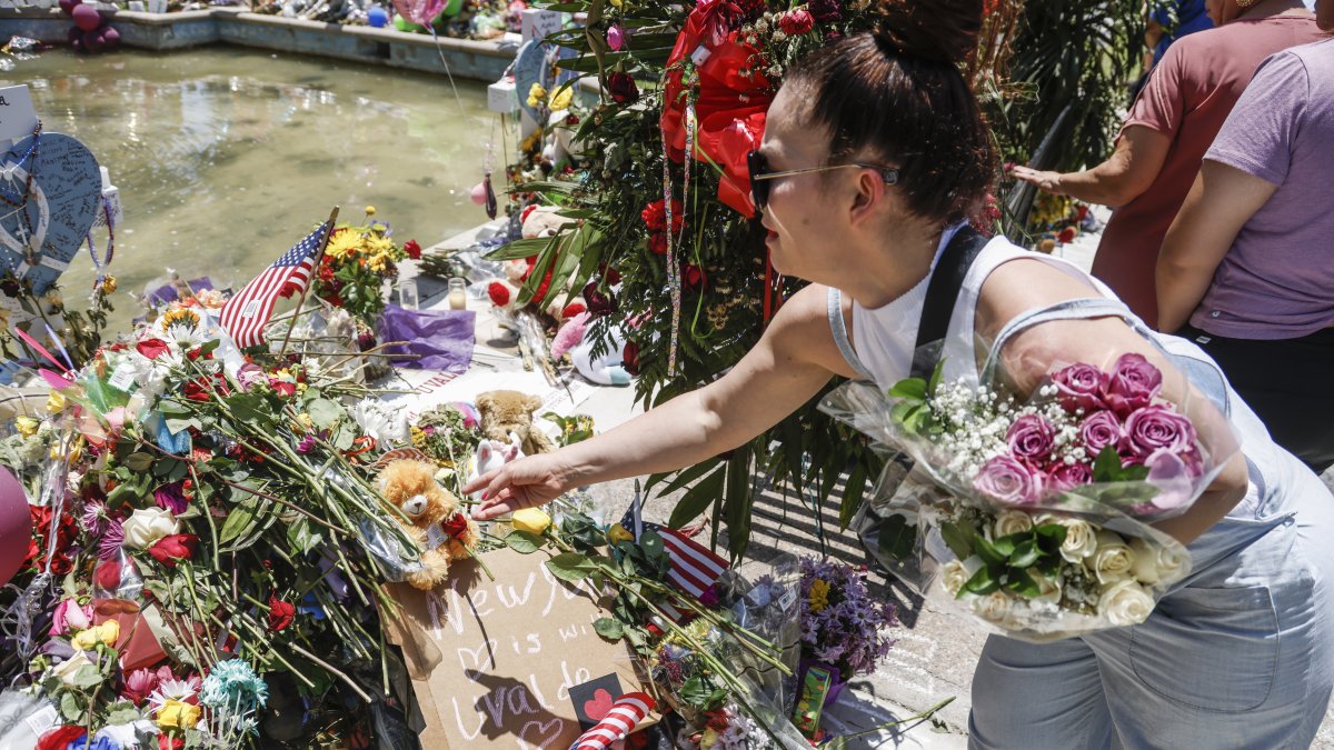 Fotografía de archivo, tomada el pasado 29 de mayo, en la que se registró a una mujer al hacer una ofrenda floral frente a la institución académica Robb Elementary School, en Uvalde (Texas, EE.UU.), luego de que un joven desadaptado asesinara a 19 niños y dos maestras e hiriera a otras 17 personas.