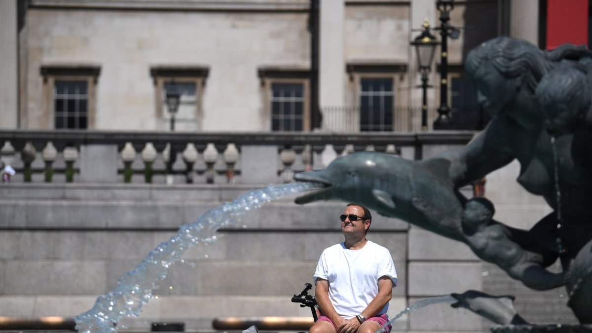 Un hombre descansa bajo una fuente en Trafalgar Square, en Londres. EFE/EPA/NEIL HALL