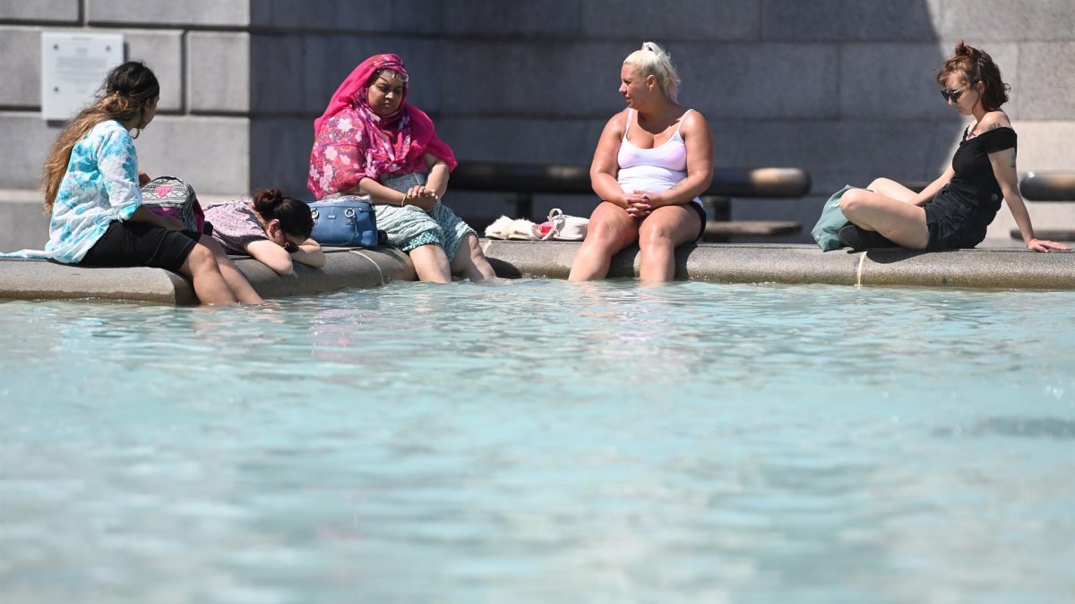 La gente se refresca en la fuente de Trafalgar Square, Londres.