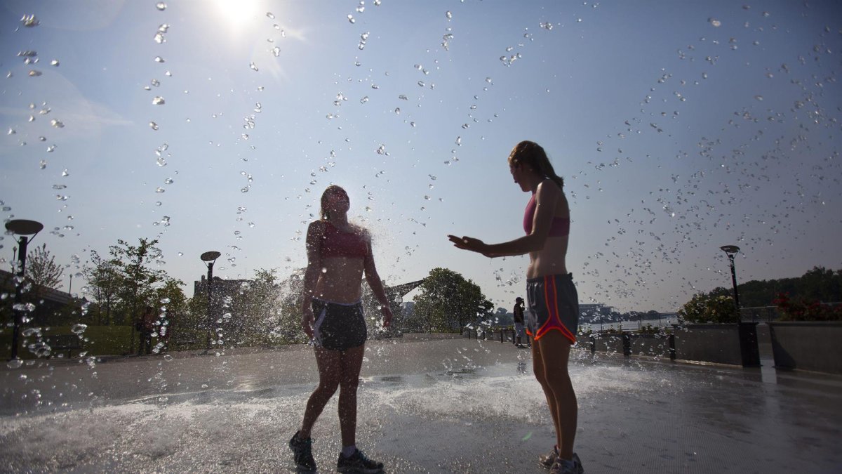 Personas se refrescan en una fuente ante las temperaturas registradas durante una ola de calor.