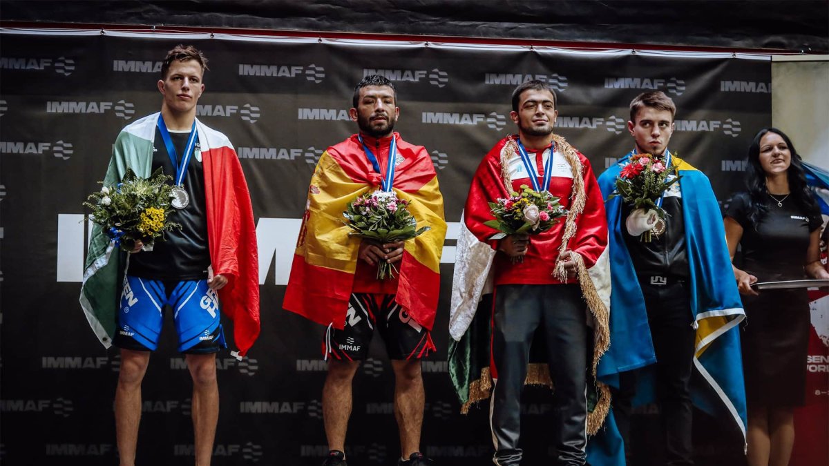 Juan Carlos con la bandera de España en el primer lugar de peso pluma IMMAF.