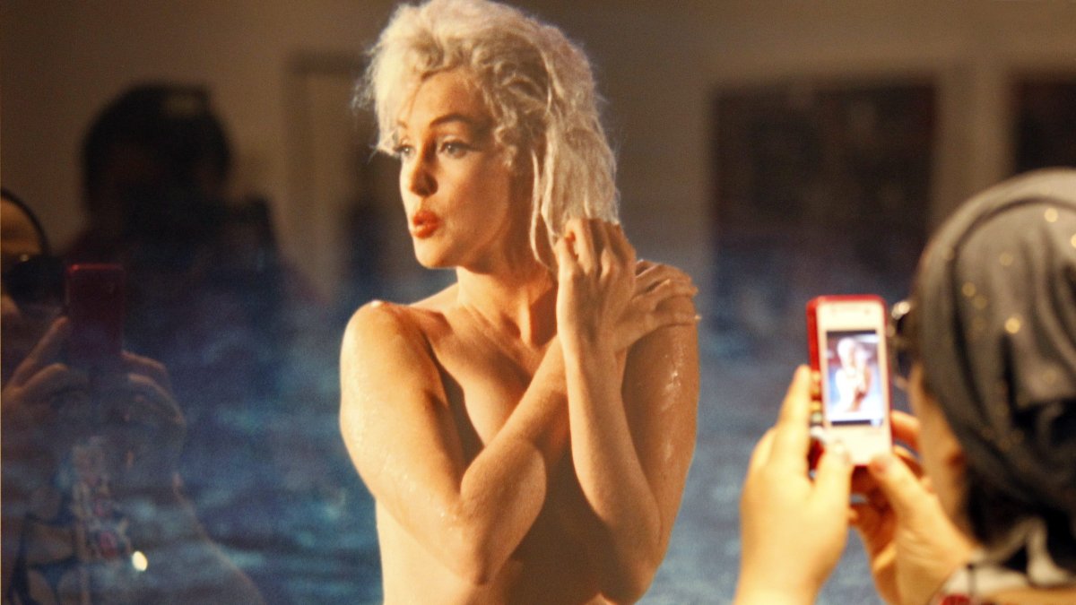 Una mujer toma una fotografía de un retrato de la actriz estadounidense Marilyn Monroe (1926-1962)