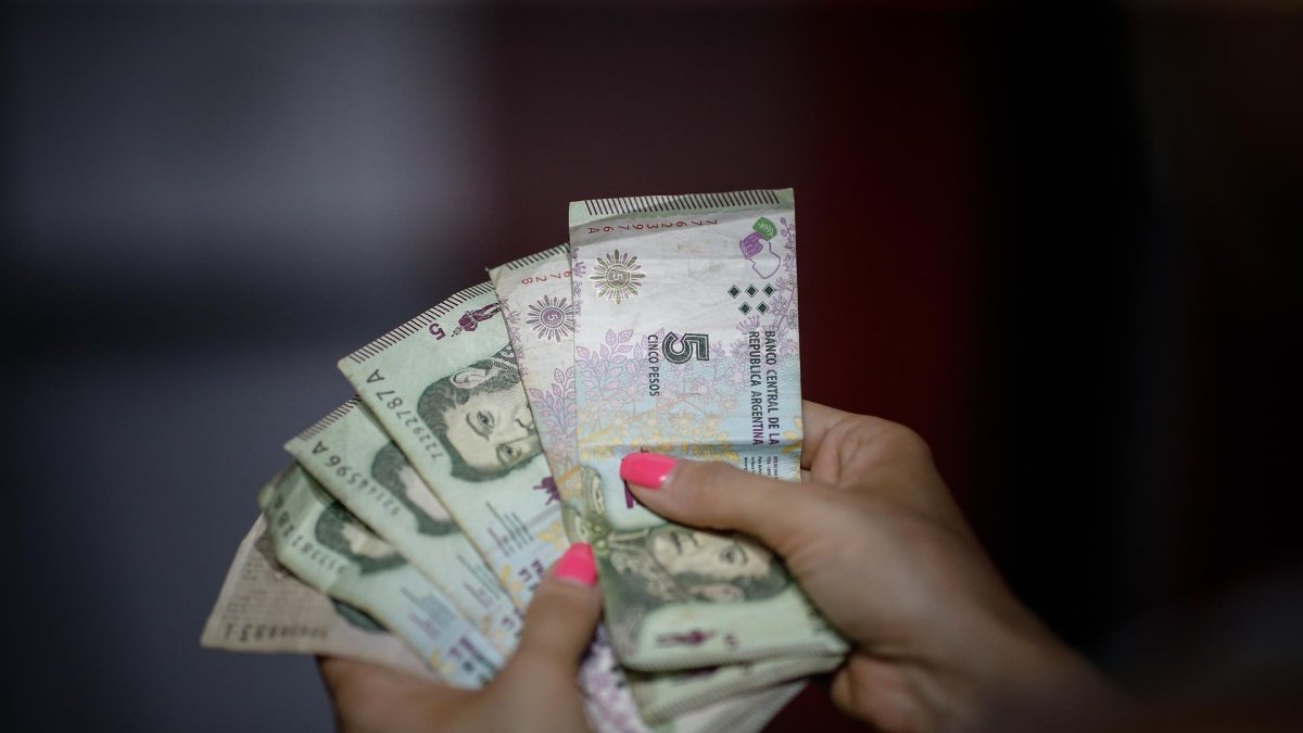 El aumento del salario mínimo en Argentina fue acordado a principios de semana entre representantes sindicales, empresarios y funcionarios estatales. En la imagen un registro de archivo de las manos de una mujer al contar un fajo de billetes de 5 pesos argentinos.