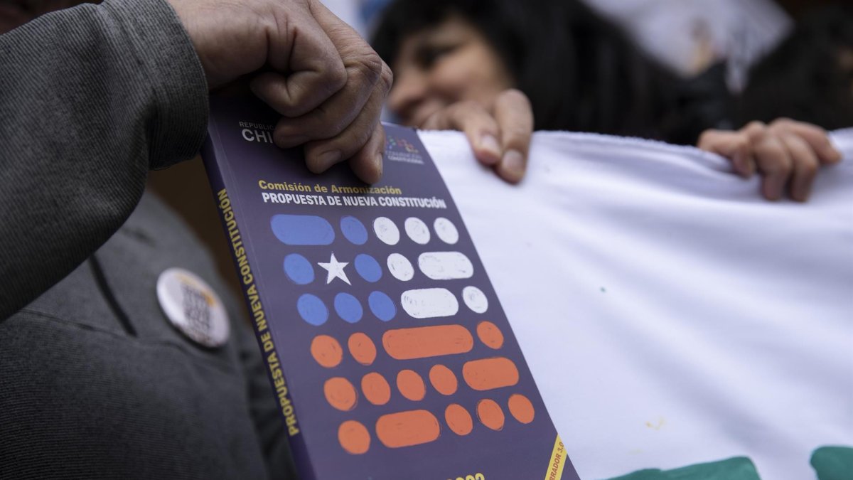 Fotografía de archivo en la que se registró la mano de un hombre al sostener un ejemplar de la propuesta de nueva Constitución chilena.