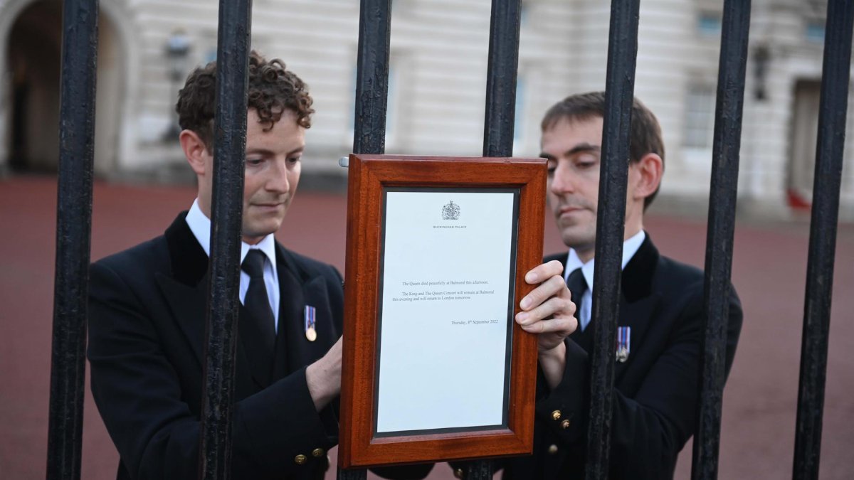 Miembros de la casa real británica publican el anuncio oficial de la muerte de la reina Isabel II en las puertas del Palacio de Buckingham este jueves.