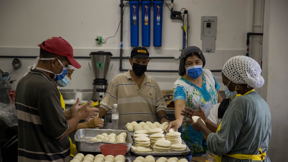 Personas preparan arepas en el marco del Día Mundial de este alimento, hoy, en Caracas (Venezuela).