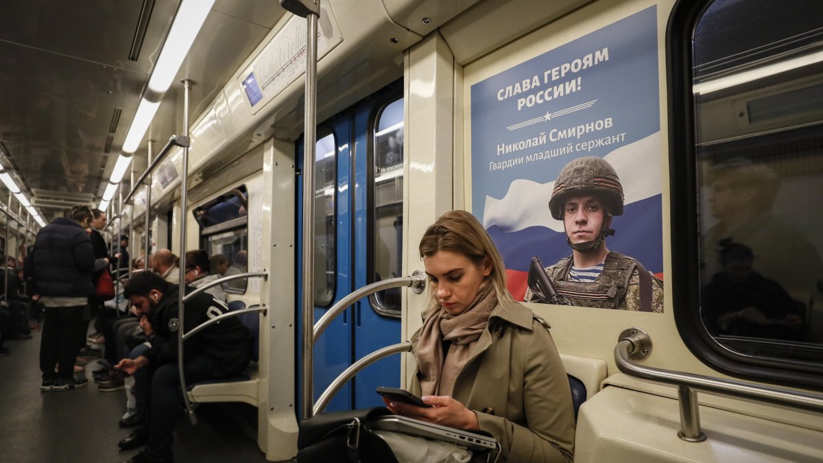 Una mujer viaja en el metro sentada frente a un cartel en el que se muestra a un soldado ruso, este martes en Moscú (Rusia).