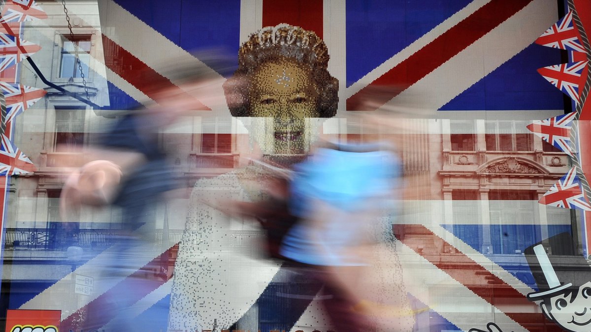 Unos niños corren frente a una imagen de la difunta reina Isabel II frente a la bandera de la Unión hecha completamente de lego en una tienda de juguetes en Londres.