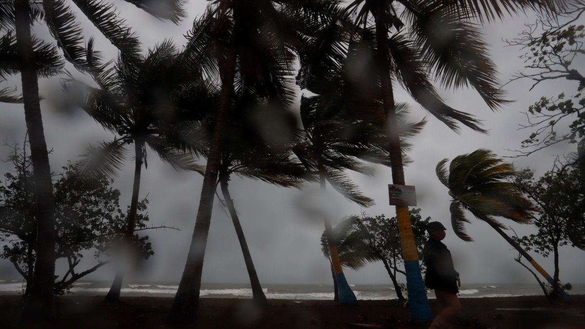 Una persona camina entre la lluvia y los fuertes vientos debido al paso de una tormenta por Puerto Rico, en una fotografía de archivo