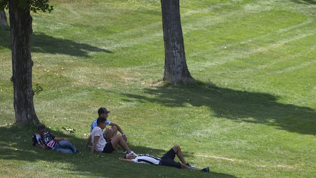 En la imagen de archivo, unos jóvenes se protegen a la sombra en un parque.
