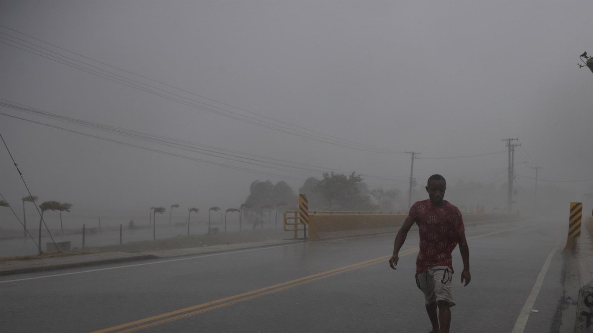 Un hombre camina en medio de una intensa ráfaga de viento y lluvia durante el paso del huracán Fiona, hoy, en Nagua (República Dominicana).
