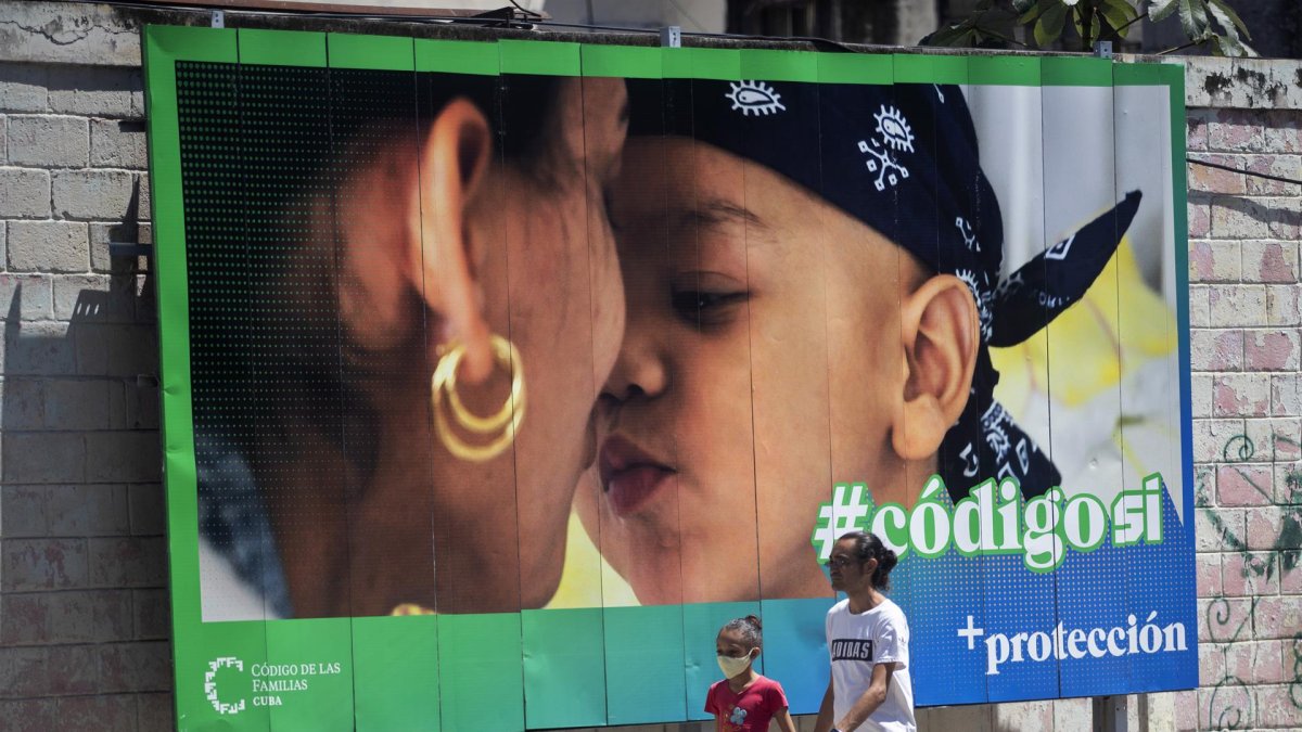 Un hombre y su hija pasan caminando frente a una valla que hace parte de la campaña por el SÍ en el referendo sobre el código de familia, hoy en La Habana (CUBA).