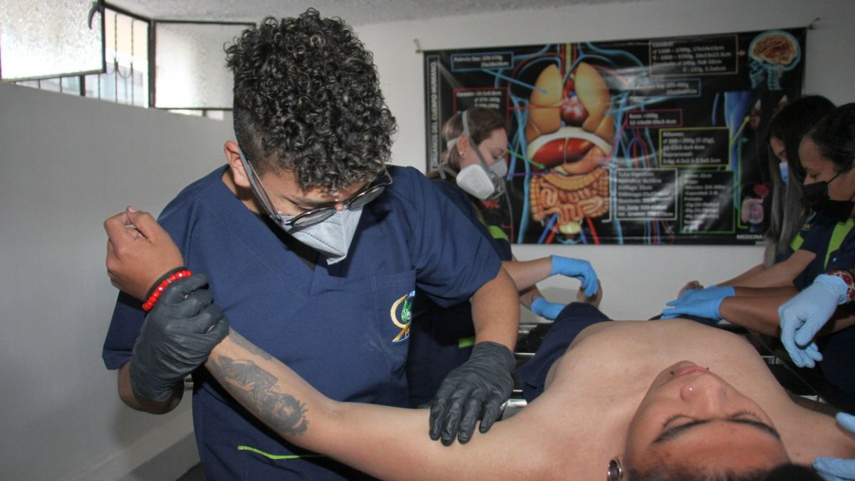 Trabajo. Uno de los estudiantes de Ortiz aprende a reconocer la anatomía y cómo manejar un cuerpo, que en este caso es otro estudiante que simula estar muerto.