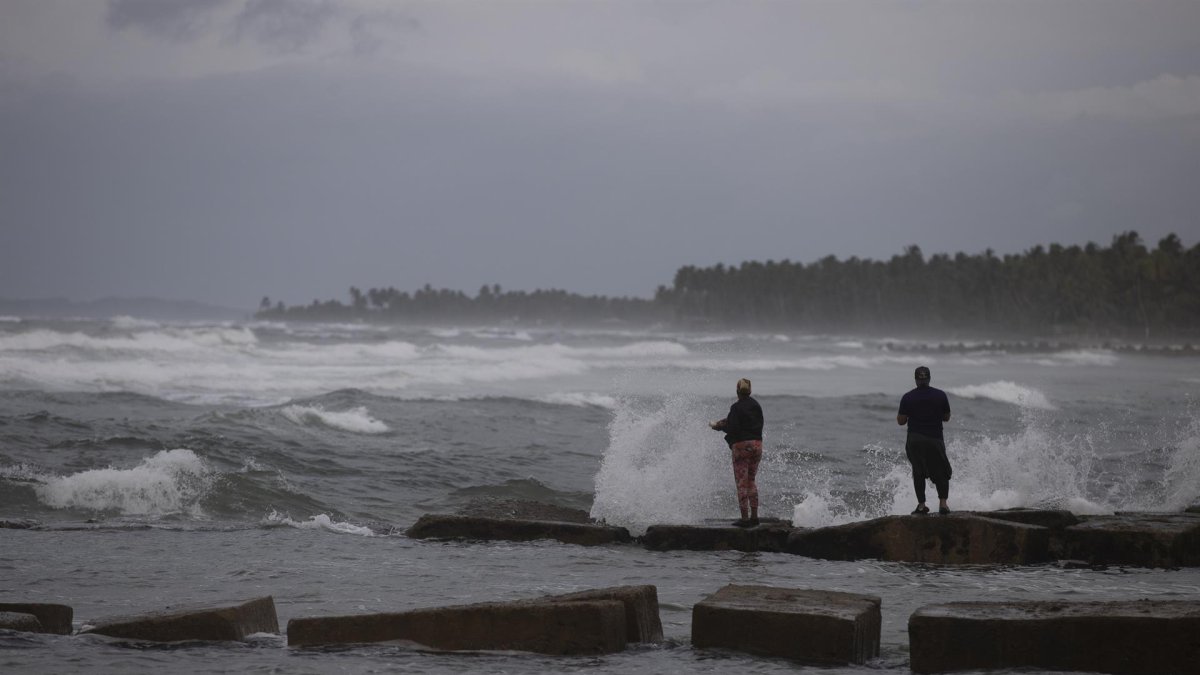Dos personas pescan en la playa hoy, mientras el país se prepara para el paso en las próximas horas del huracán Fiona, en Nagua (República Dominicana).