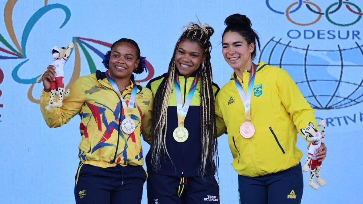 La pesista ecuatoriana Angie Palacios como monarca absoluta de los 76 kilogramos junto a competidoras colombiana y brasileña durante los Juegos Suramericanos.