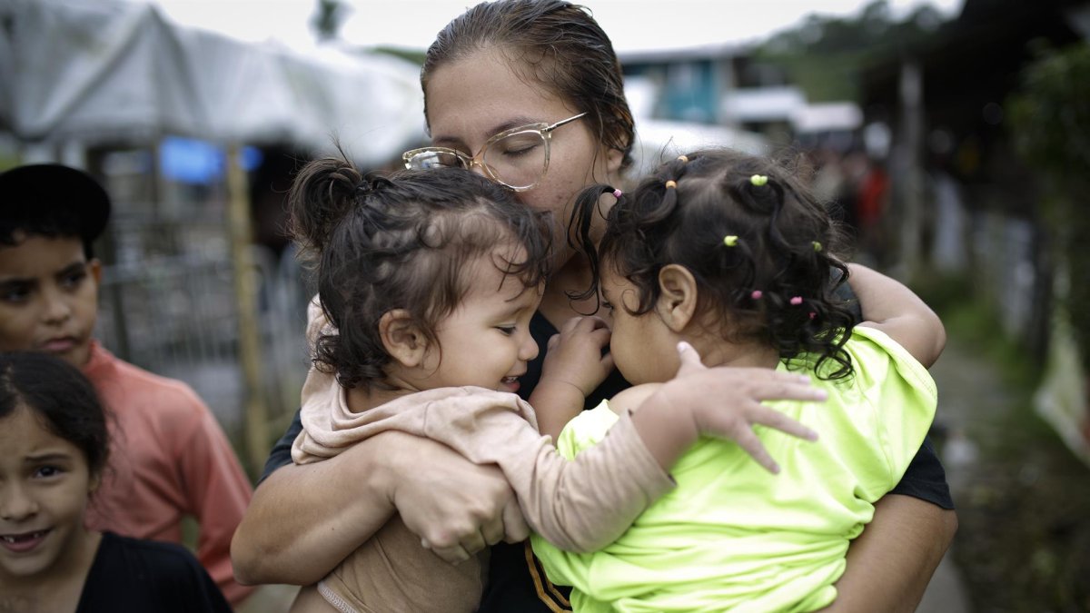 Dairana Moreno, migrante venezolana de 30 años, carga a su hija Salma Bracho (i) y otra menor, el 13 de octubre de 2022, en el pueblo de Bajo Chiquito (Panamá).
