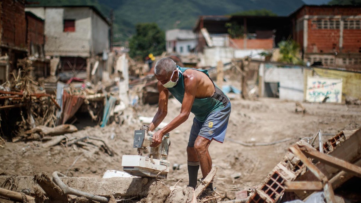 Un hombre fue registrado al buscar objetos para rescatar entre los escombros, tras los derrumbes provocados por las fuertes lluvias, en Las Tejerías (Venezuela).