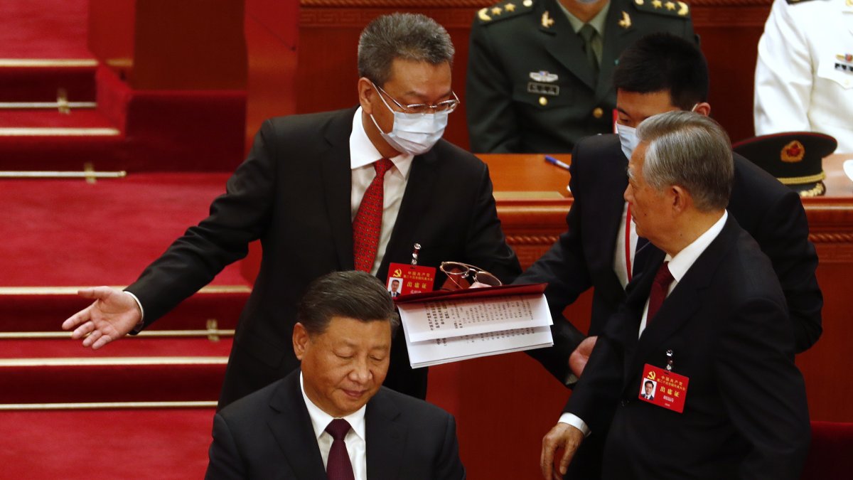 Hecho. El expresidente de China Hu Jintao (derecha) es conducido mientras el presidente Xi Jinping (izquierda) observa durante la ceremonia de clausura del congreso.