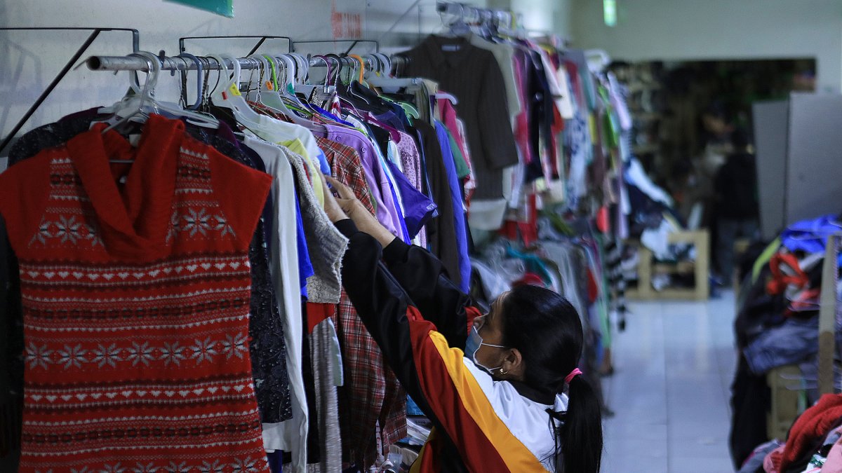 Una mujer migrante venezolana selecciona ropa donada por activistas para afrontar el frio en 