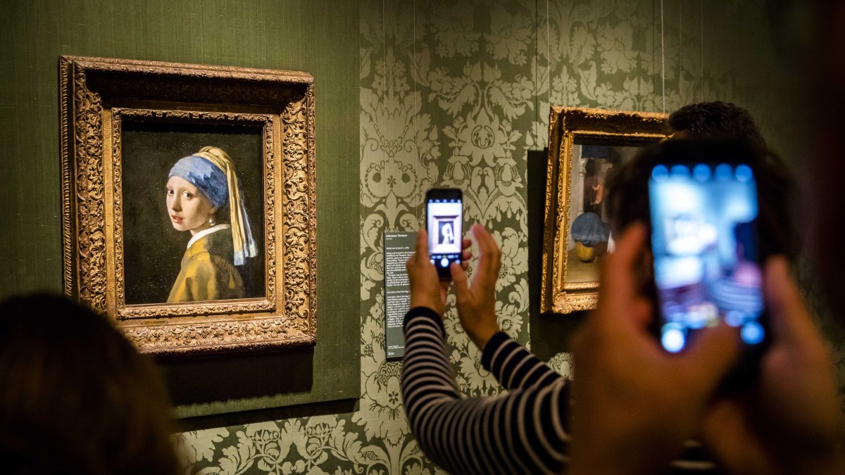 Visitantes toman fotografías de la 'Niña de la Perla', del artista holandés Johannes Vermeer, en el Museo Mauritshuis de La Haya, en Países Bajos.