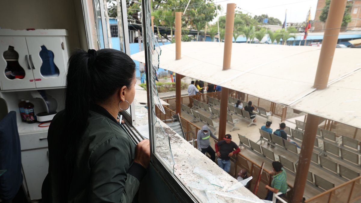 Destrucción. Entre los ventanales rotos de su departamento, Gabriela Pino observa los trabajos de reconstrucción en los bajos del edificio que fue afectado por la explosión de una bomba, afuera del Municipio de Durán.