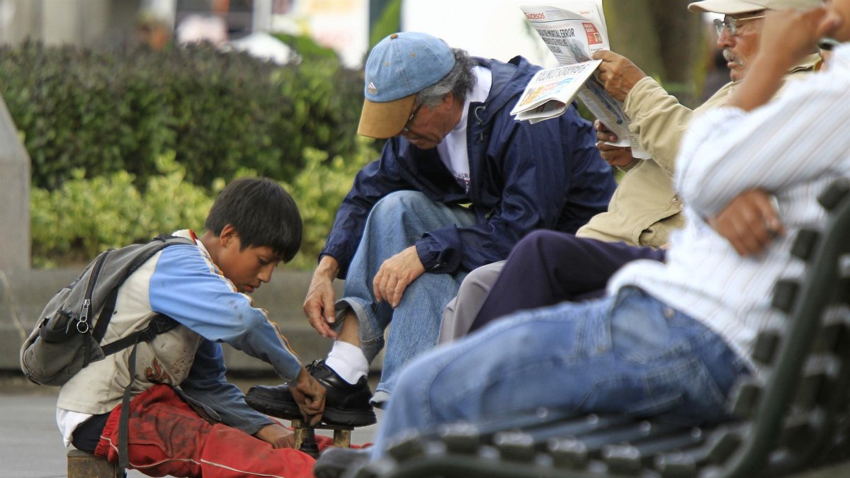 Fotografía de archivo en la que se registró a un niño al trabajar lustrando zapatos en una calle de Quito (Ecuador).