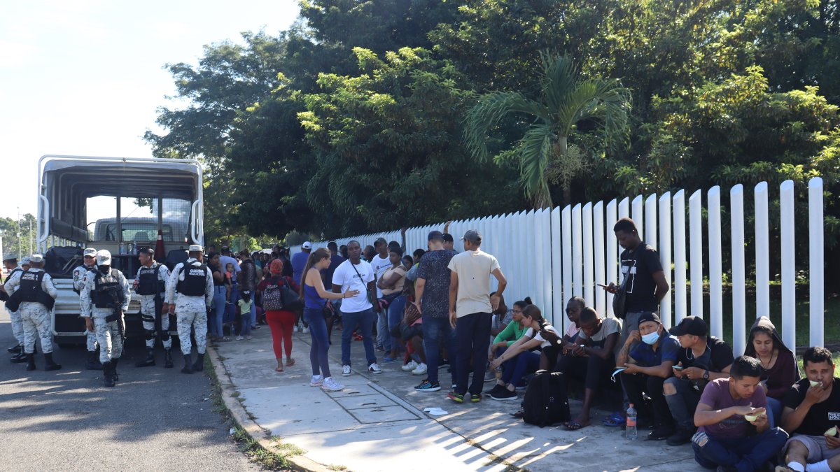 Migrantes hacen fila para intentar resolver su situación migratoria a las afueras del módulo de atención provisional ubicado en el parque ecológico, hoy, en Tapachula (México).