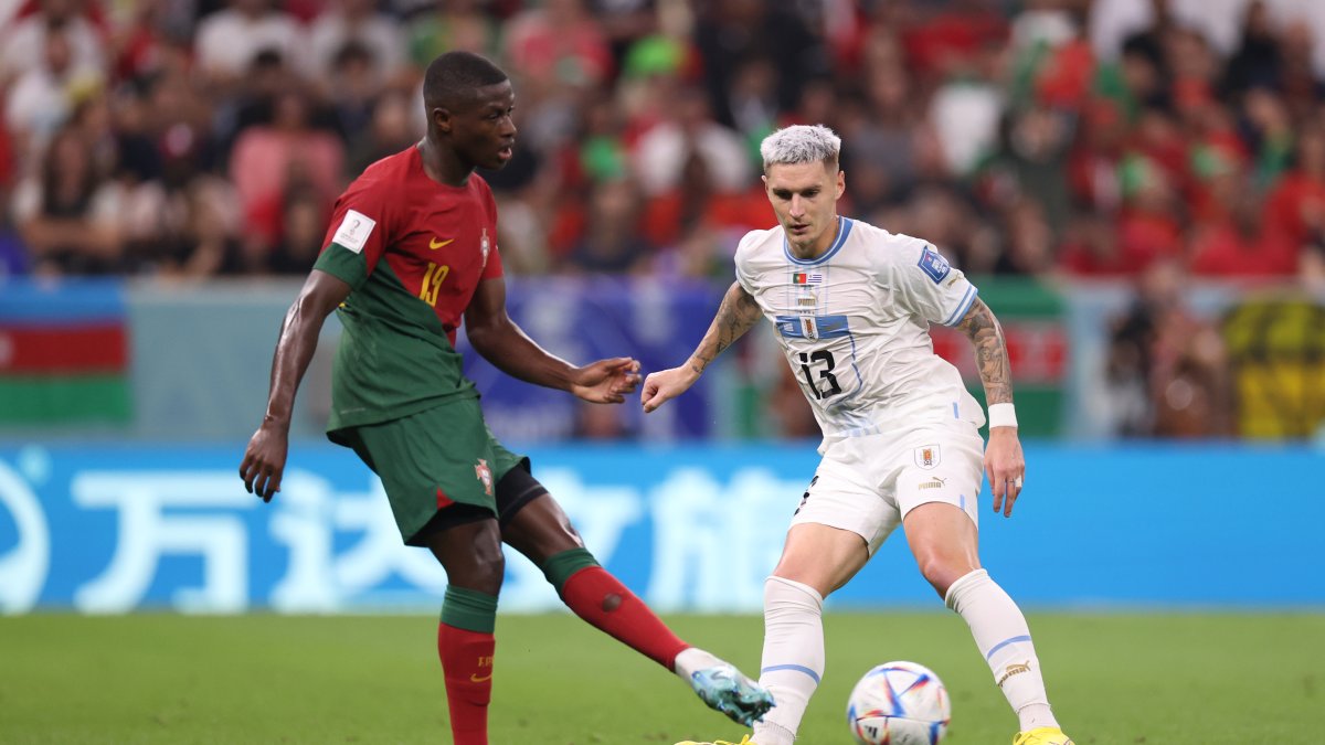 Nuno Mendes (i), defensor portugués, disputa una pelota con el uruguayo Guillermo Varela.
