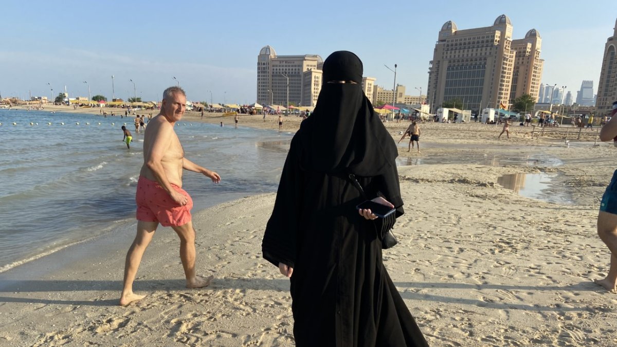 Una joven árabe camina con su indumentaria habitual por la playa. Para tomarle una foto se debió pedir permiso, son las normas.