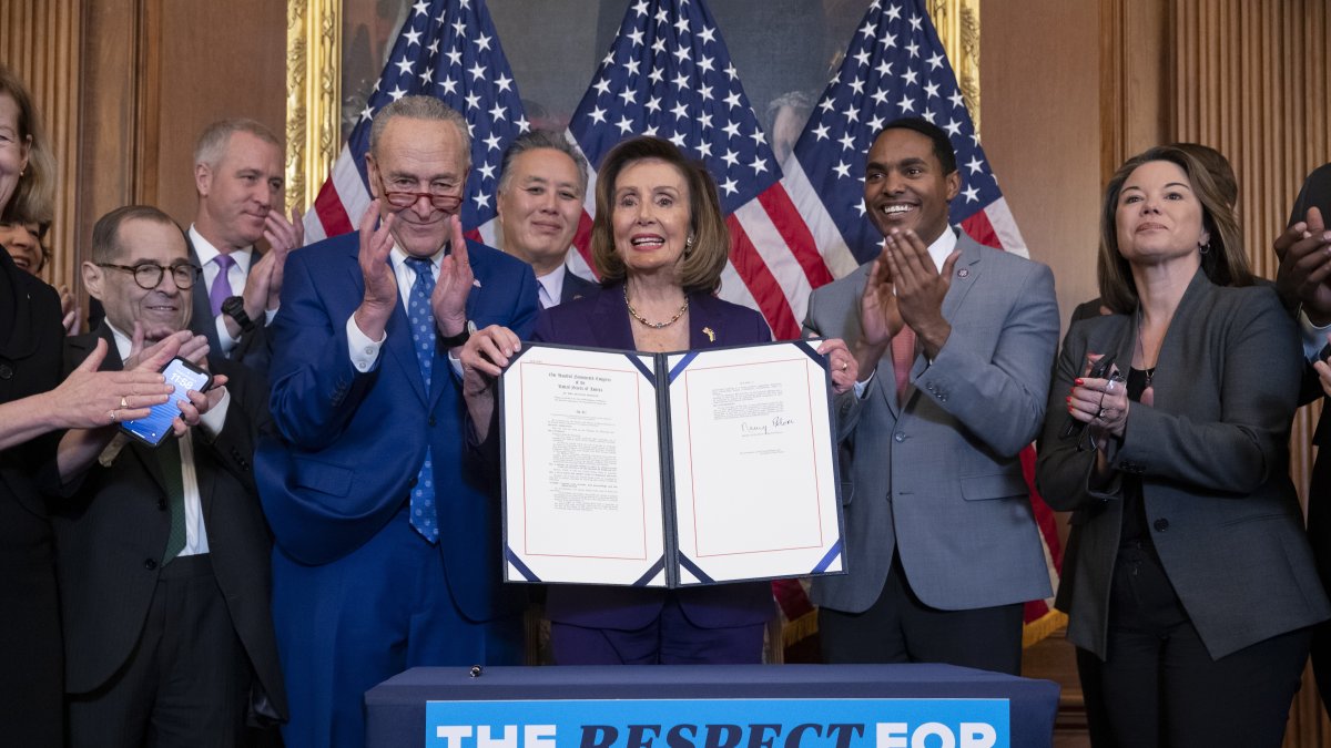 La presidenta de la Cámara de Representantes, Nancy Pelosi (c), sostiene el proyecto de ley que blinda a nivel federal el matrimonio entre personas del mismo sexo.