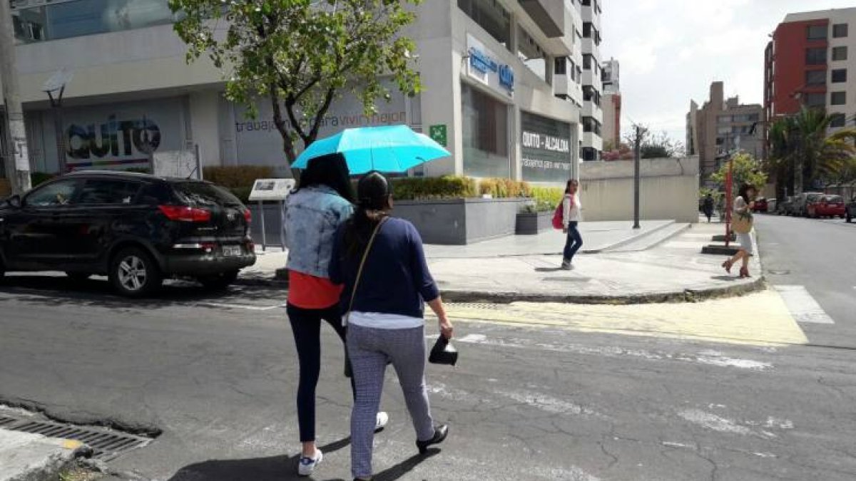 Referencia. Ciudadanos, en Quito, se cubren del sol con paraguas.