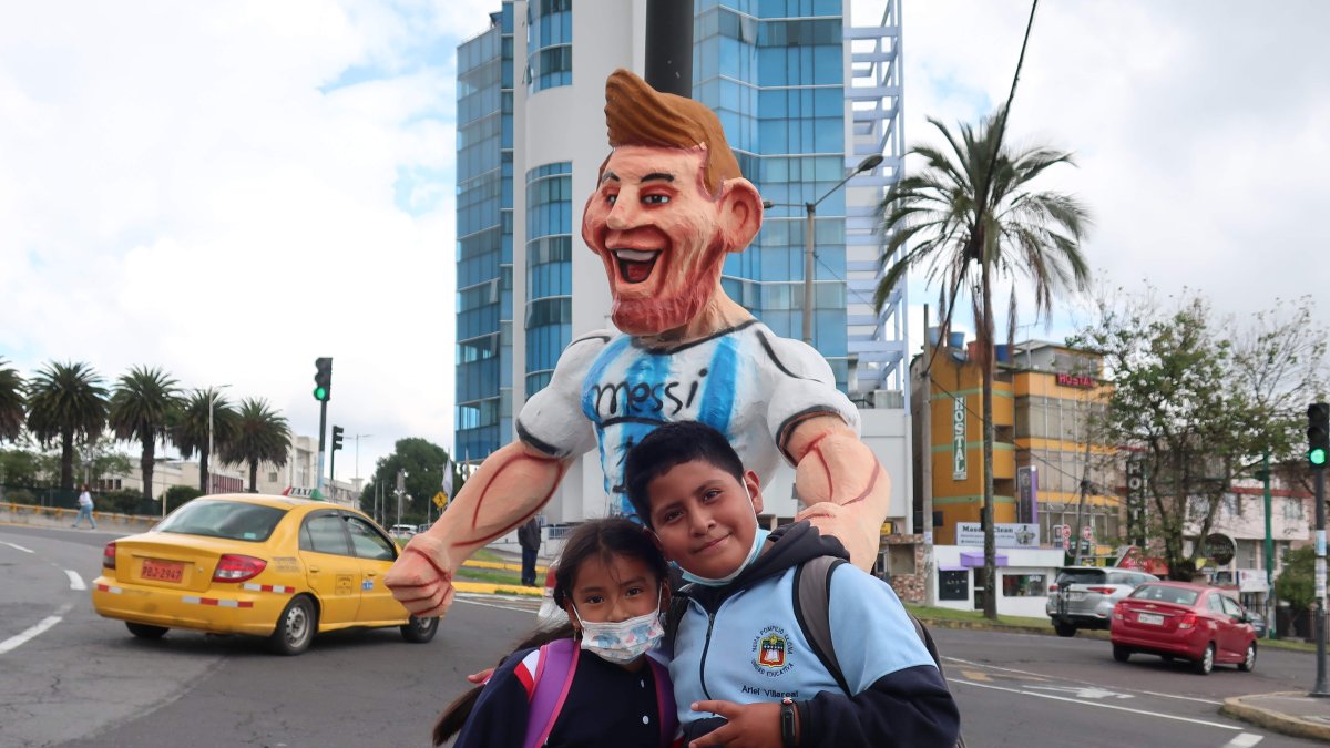 Dos niños posan junto a un monigote de Lionel Messi, el 28 de diciembre de 2022, en Quito (Ecuador).