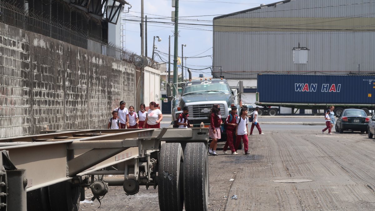 Los alumnos del José María Egas caminan entre los camiones parqueados en los alrededores del colegio.