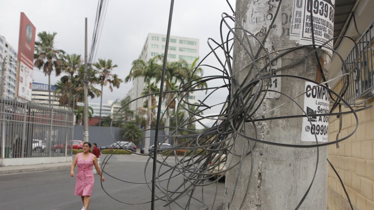 En la calle 10 y B de la ciudadela Adace hay cables enredados en postes y otros que están colgados.