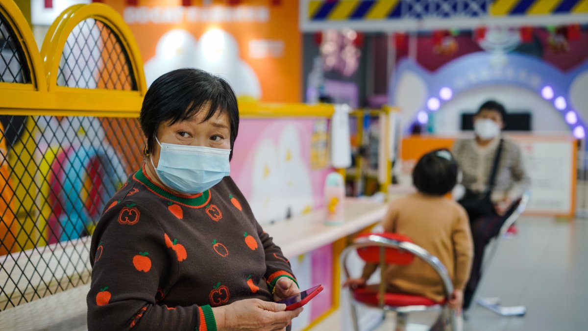 Una mujer protegida con una mascarilla utiliza su móvil en un centro comercial de Pekín este 11 de enero. 