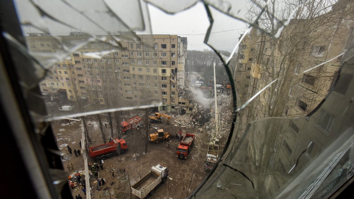 Efecto. Una vista tomada a través del vidrio roto de una ventana con vista al sitio de un edificio residencial dañado mientras continúan los trabajos de rescate.