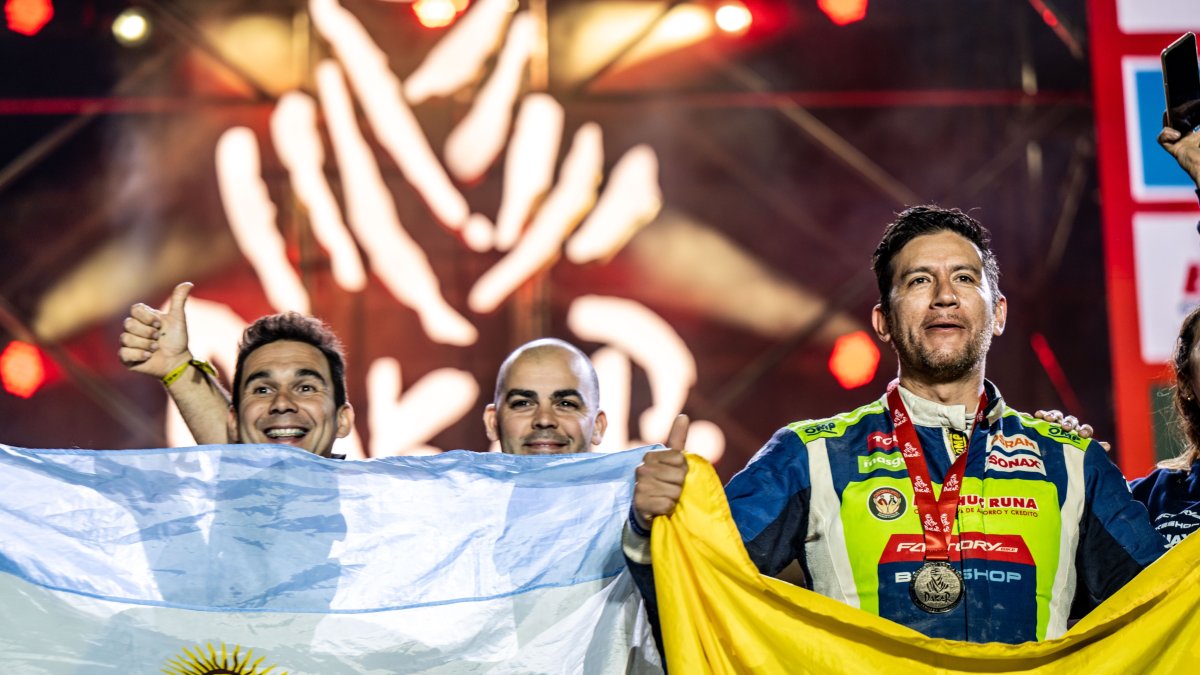 El piloto Sebastián Guayasamín (d) y su celebración con la bandera ecuatoriana tras concluir el rally Dakar.