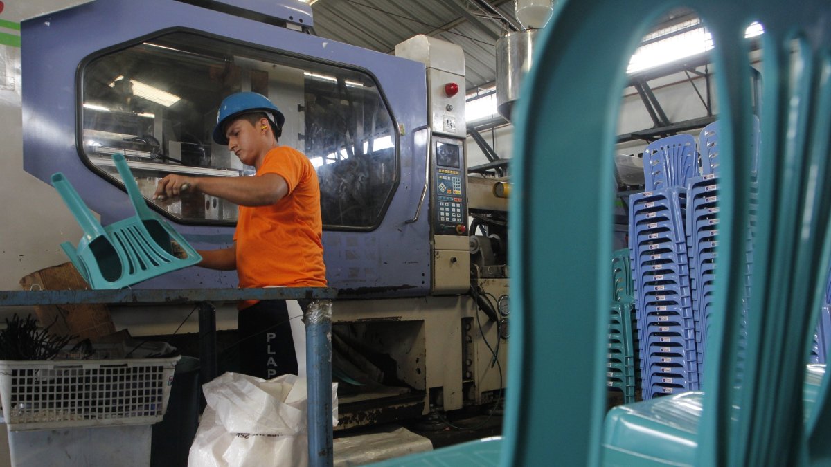 Industria. Una persona en planta que elabora sillas plásticas.