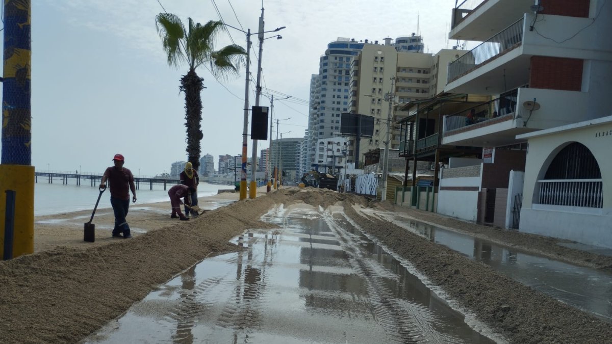 Personal del Municipio de Santa Elena retirando la arena de la playa que se encontraba en la vía.