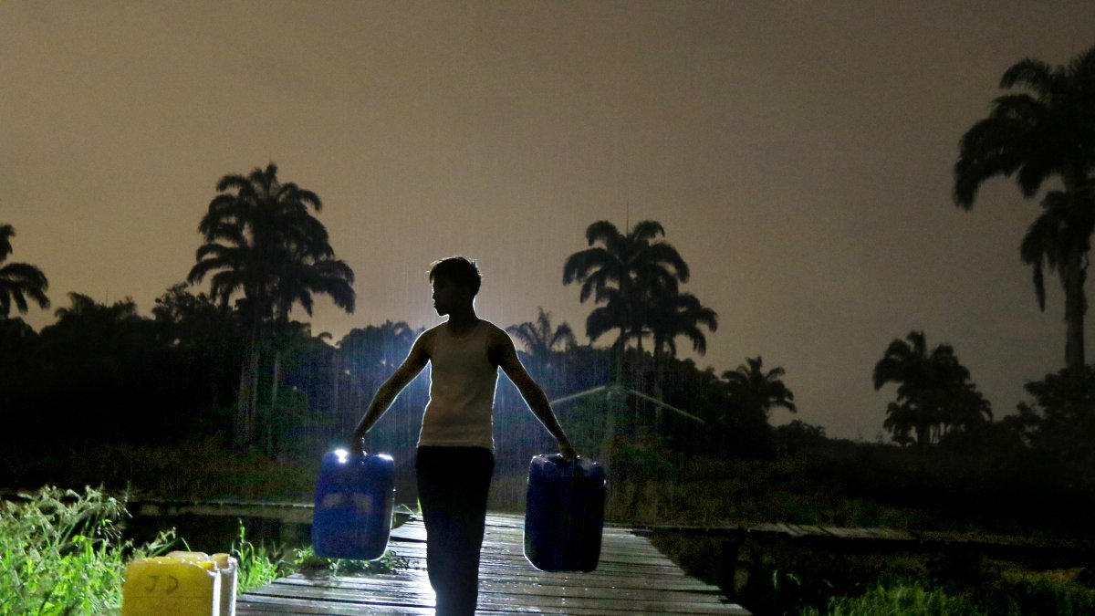 Los comuneros a oscuras van en busca de sus baldes llenos de agua por la lluvia