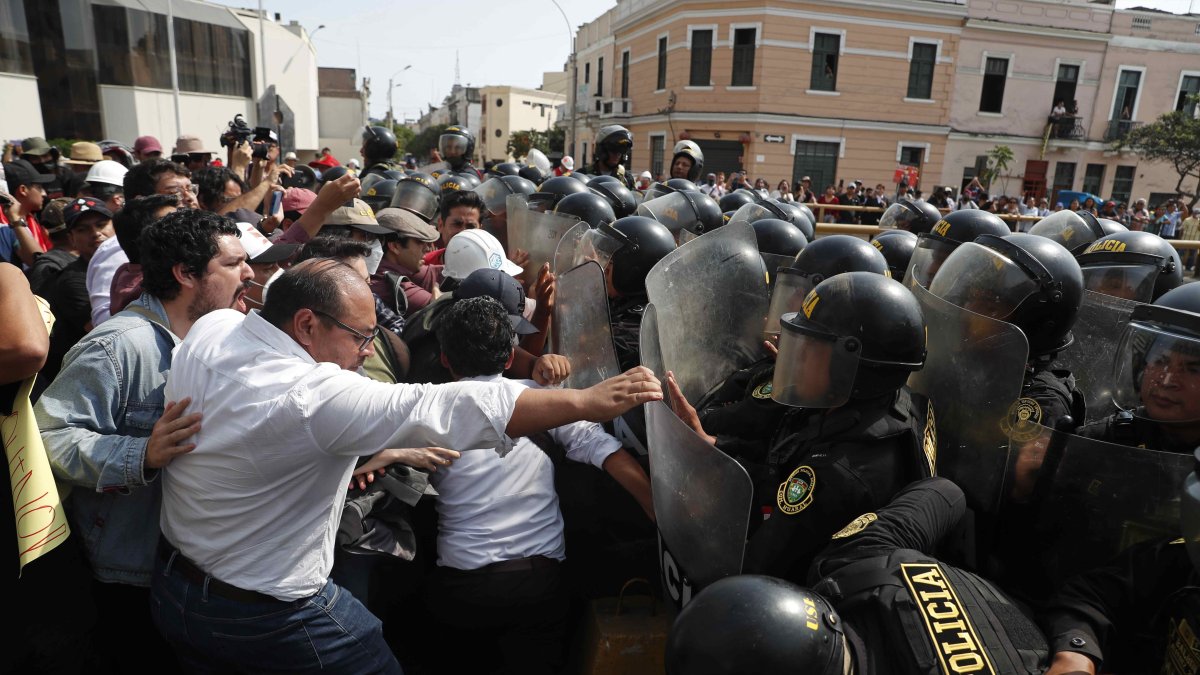 Policías chocan con ciudadanos junto a la sede de la Prefectura, donde se encuentran los manifestantes detenidos, en Lima